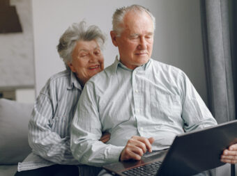 Elegant old couple sitting at home and using a laptop