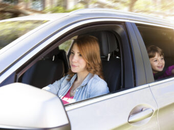 Woman driving car with girl on backseat